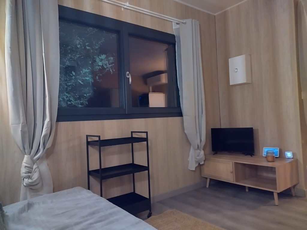 Chambre de la tiny house, boiseries claires et grande fenêtre