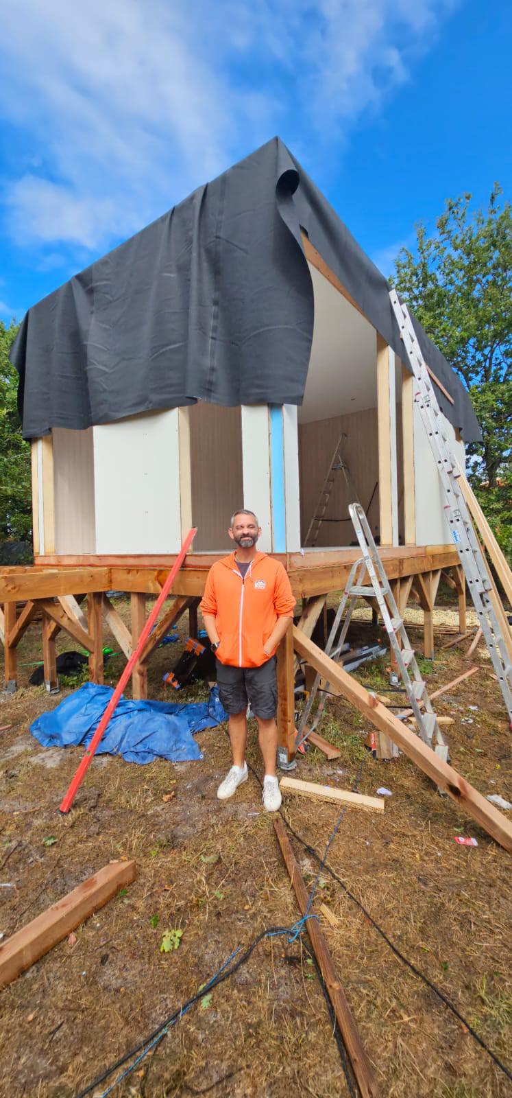 Valerian devant la tiny house en construction, sur pilotis
